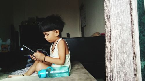 Side view of boy using mobile phone at home