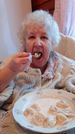 Portrait of senior woman eating dumplings at home