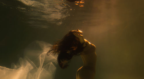 Woman with curtain swimming in pool