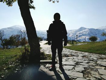 Rear view of man standing on mountain against sky