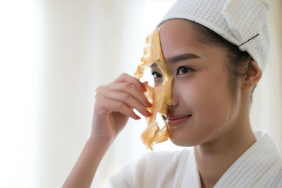 Young woman removing facial mask from face in spa