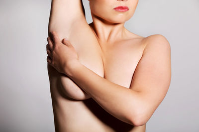 Midsection of shirtless woman against white background