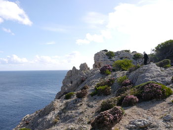 Scenic view of rocks by sea against sky