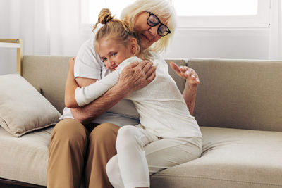 Mother and daughter sitting on sofa at home