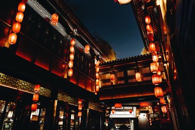 Low angle view of illuminated lanterns hanging by buildings in city at night