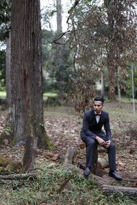 Man sitting on tree stump in forest