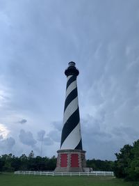 Low angle view of lighthouse by building against sky