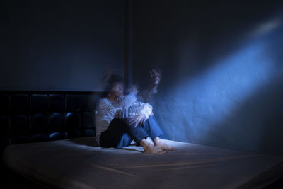 Digital composite image of couple sitting in the dark