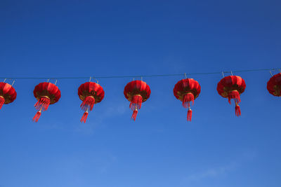 Low angle view of lanterns hanging against blue sky