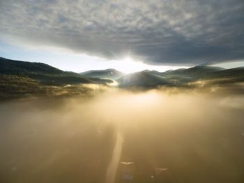 Sunlight streaming through clouds over landscape