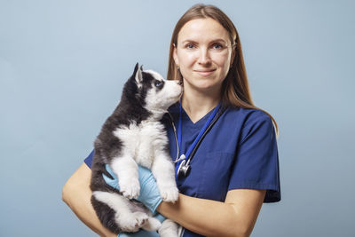 Portrait of young woman with dog against white background