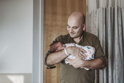 Father holding newborn boy wrapped in blankets in hospital