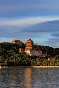 Buildings by river against sky