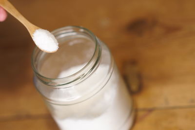 Close-up of salt in wooden spoon and jar on table