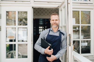 Portrait of restaurant owner standing by door