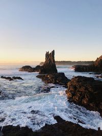 Rock formation on beach against sky during sunset