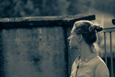 Thoughtful mature woman looking away while standing against wall