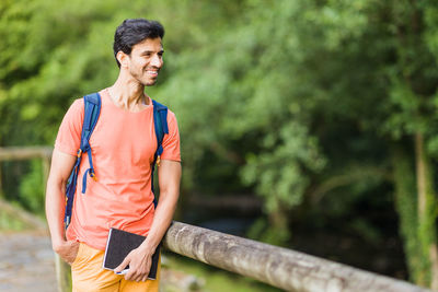 Young man looking away while standing outdoors