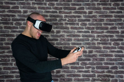 Man using mobile phone against brick wall