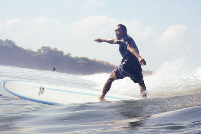 Full length of man surfing in sea against sky