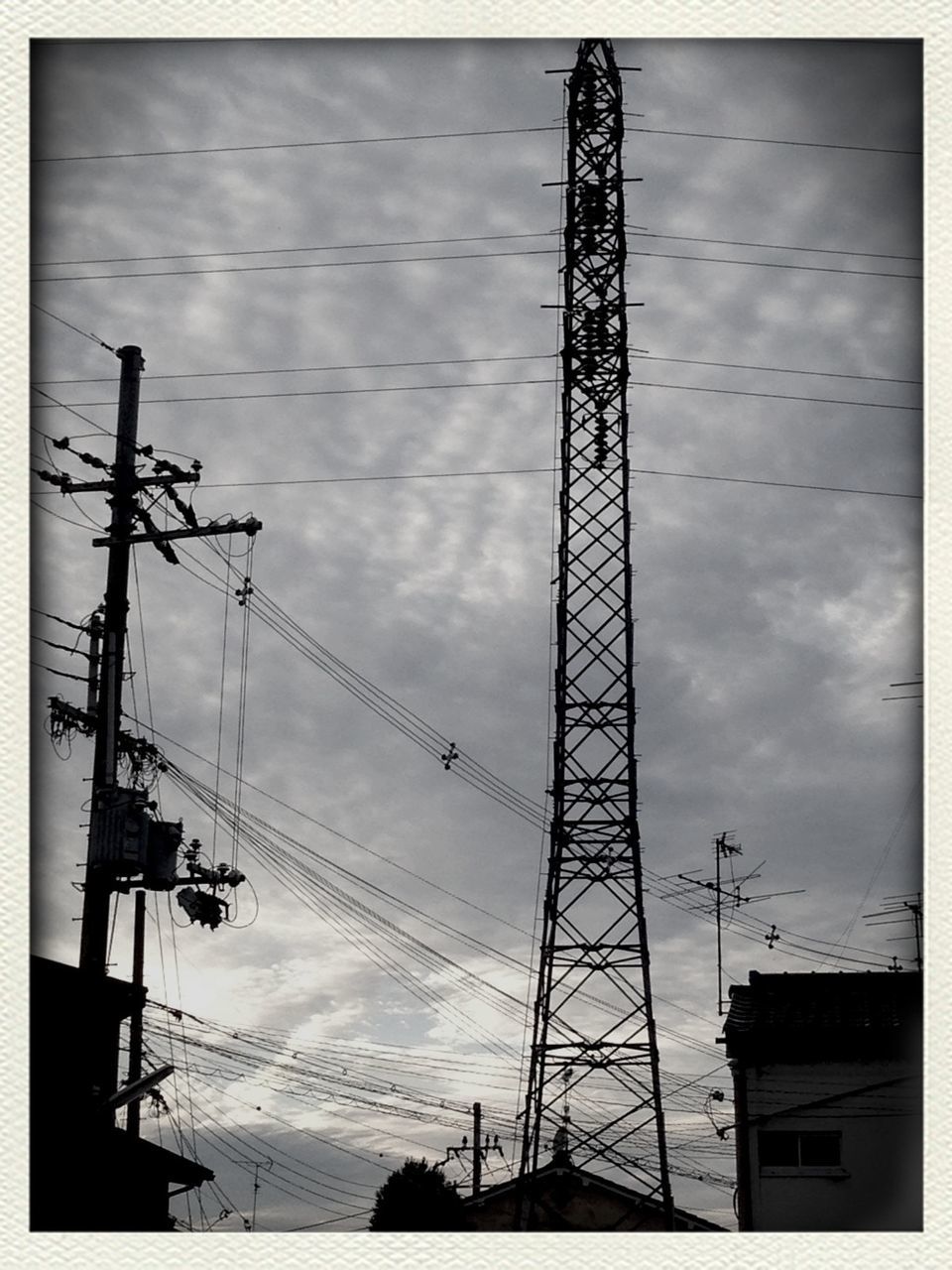 low angle view, power line, electricity pylon, power supply, sky, silhouette, connection, electricity, transfer print, built structure, architecture, cable, technology, auto post production filter, fuel and power generation, cloud - sky, building exterior, tall - high, dusk, cloudy