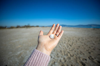Midsection of person hand on land against sky