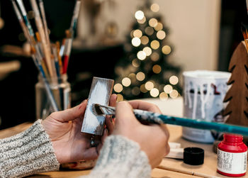 Selective focus, close-up of hand holding paintbrush, crafting christmas ornaments.