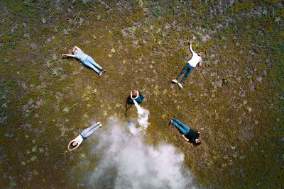 High angle view of woman with friends holding smoke bomb on field