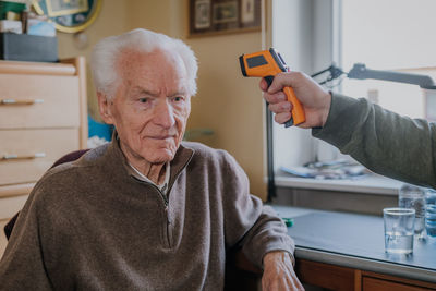 Cropped hand checking temperature of senior man