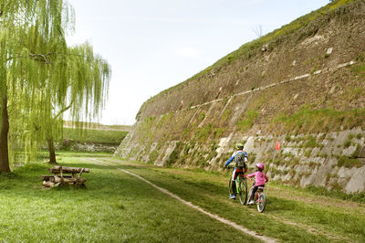 Rear view of people riding bicycle on grass