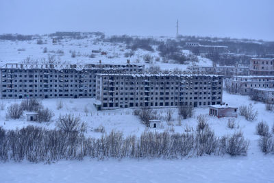 Buildings on snow covered field against sky