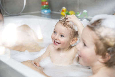 Little boy having fun in bathtub with brother and father