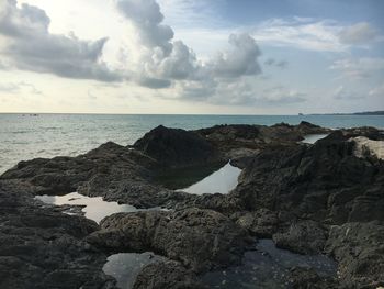 Rock formations on shore against sky