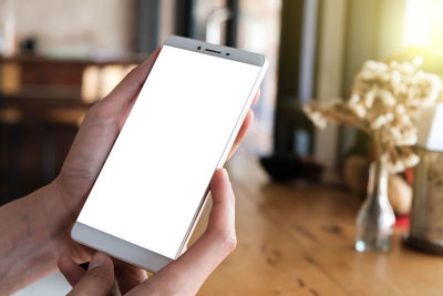 Midsection of person holding mobile phone on table