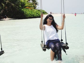 Woman sitting on swing over sea