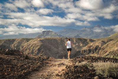 Rear view of man running on mountain against sky