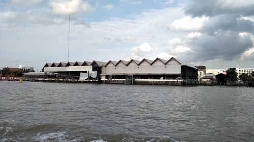 Stilt houses on beach by sea against sky