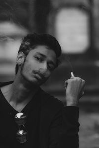 Portrait of young man smoking cigarette outdoors