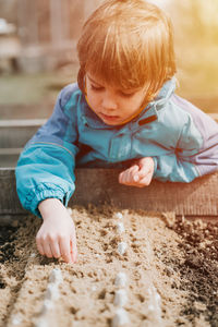 Spring planting seeding farm garden. little kid boy farmer gardener plants sow vegetable seeds soil