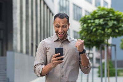 Portrait of young man using mobile phone in city