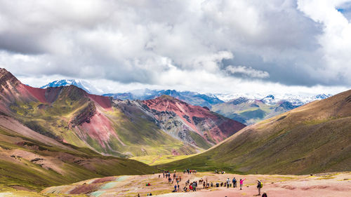 People on land against mountains and sky