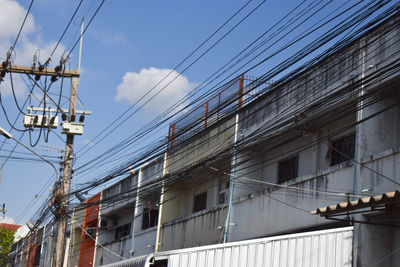 Low angle view of cables against buildings in city