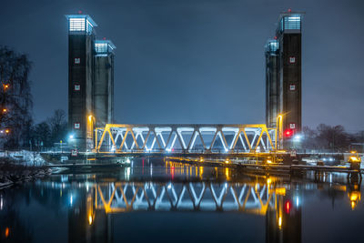 Illuminated bridge over river at night