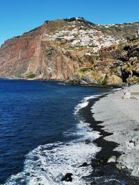 Scenic view of sea and mountains against clear blue sky