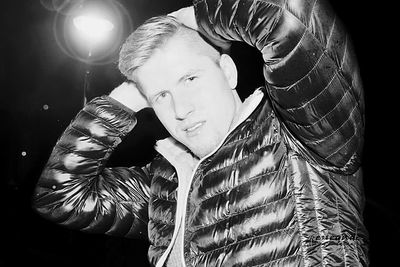 Close-up of man holding hair over black background