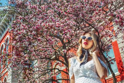 Portrait of young woman wearing sunglasses against red wall