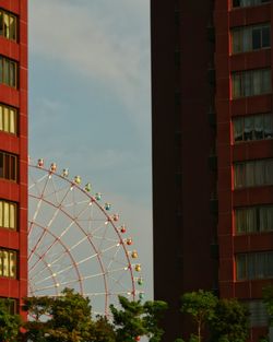 Low angle view of ferris wheel against buildings in city