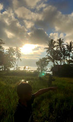 Rear view of man on palm trees against sky during sunset