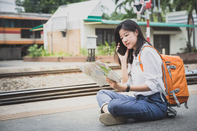 Full length of woman sitting on railroad track