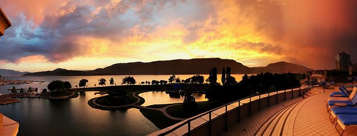 Panoramic view of swimming pool by lake against sky during sunset